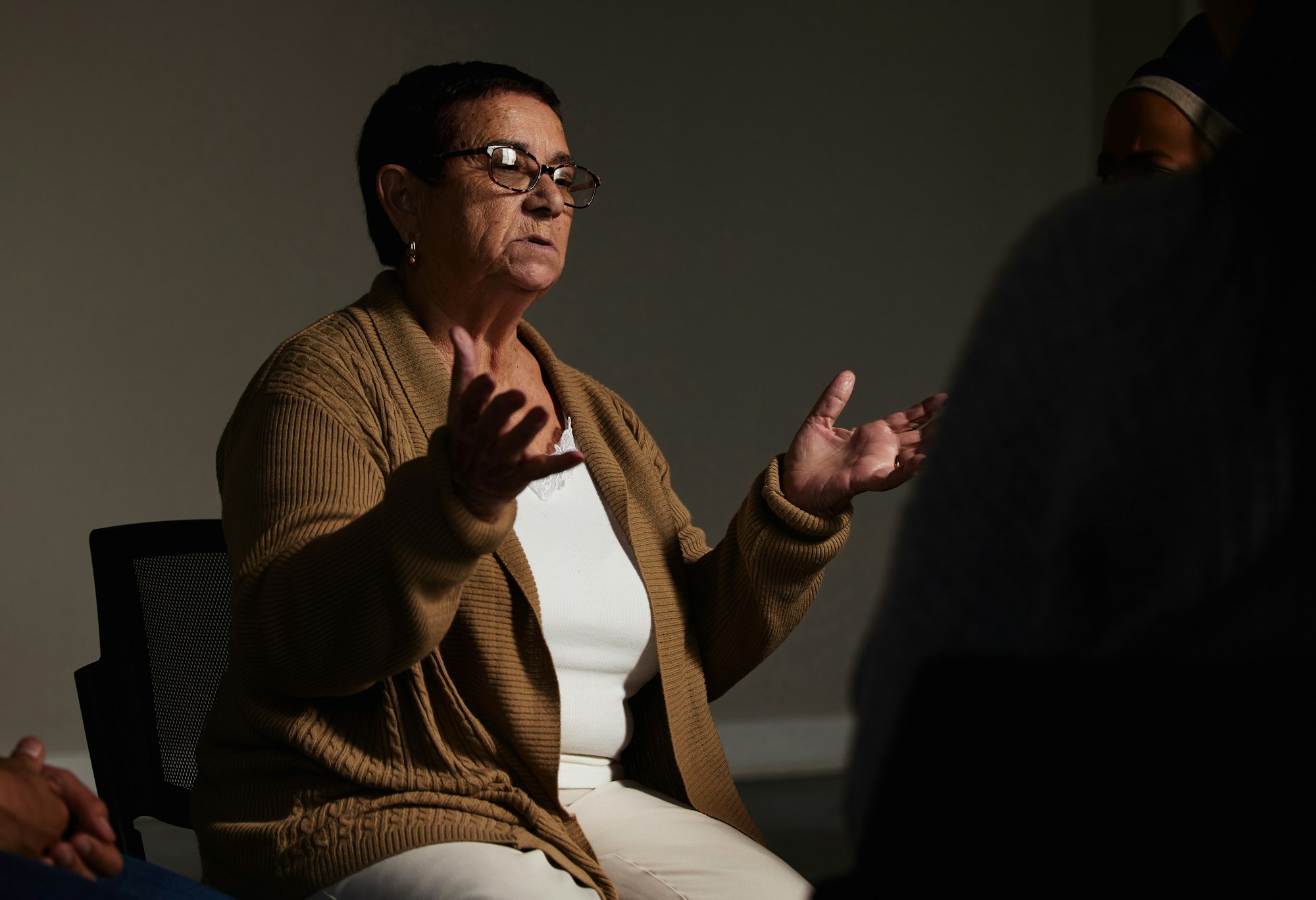 Counselling, mental health and a senior woman talking for therapy, meeting or psychology in a dark